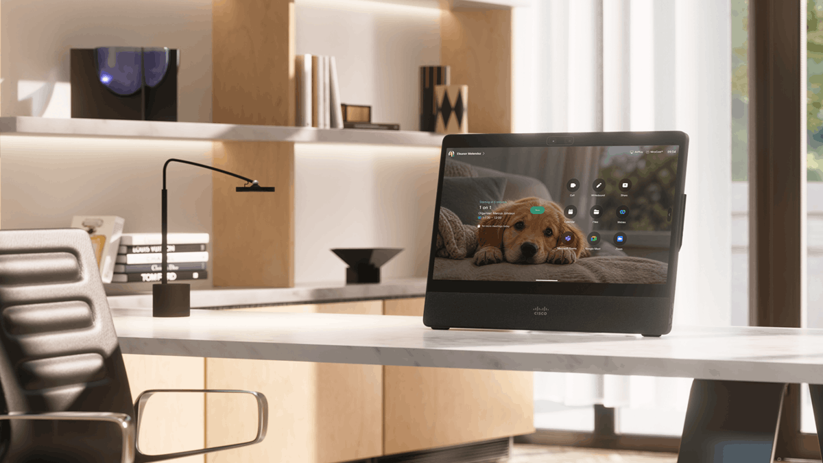 Cisco Desk device displaying a personalized puppy wallpaper and meeting controls on a modern home office desk