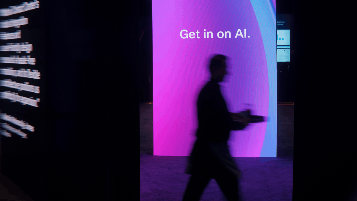 A person walks through a WebexOne 2026 exhibit featuring a large illuminated “Get in on AI” display