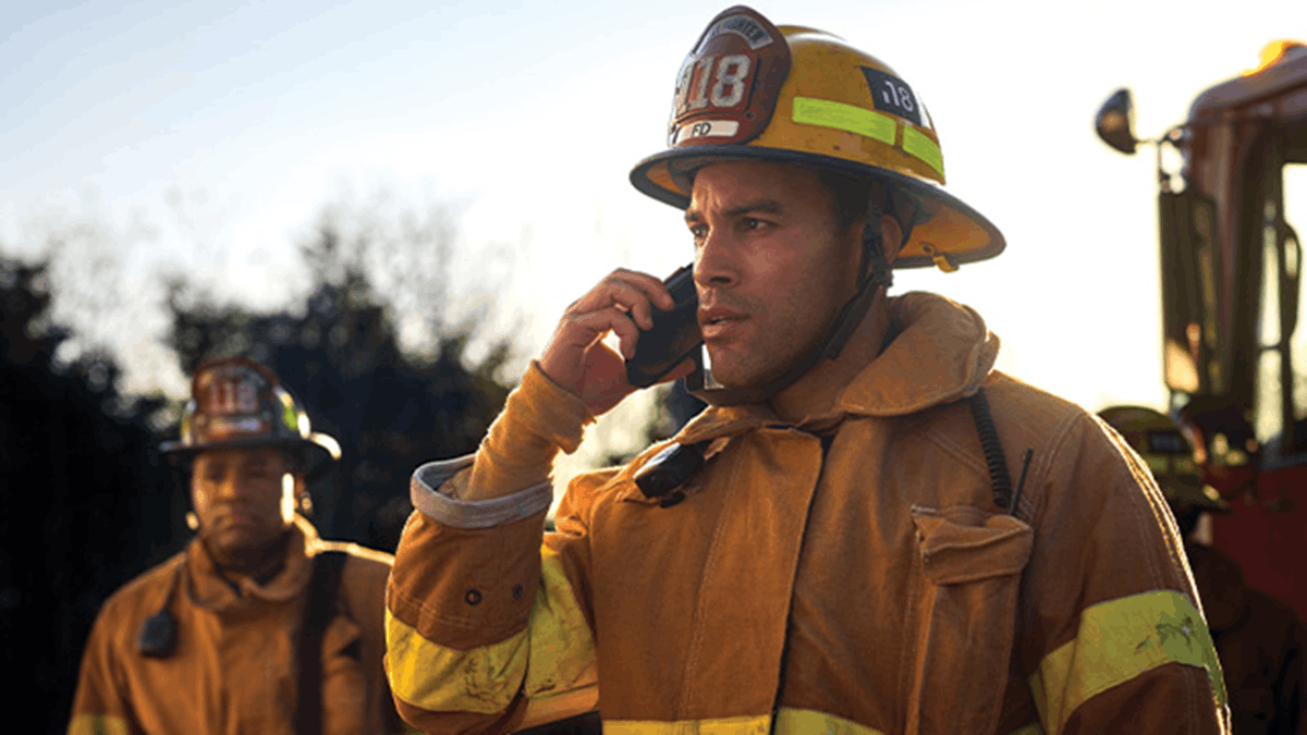 First responder using a mobile device during an emergency, representing connected communication and coordination enabled through public safety networks