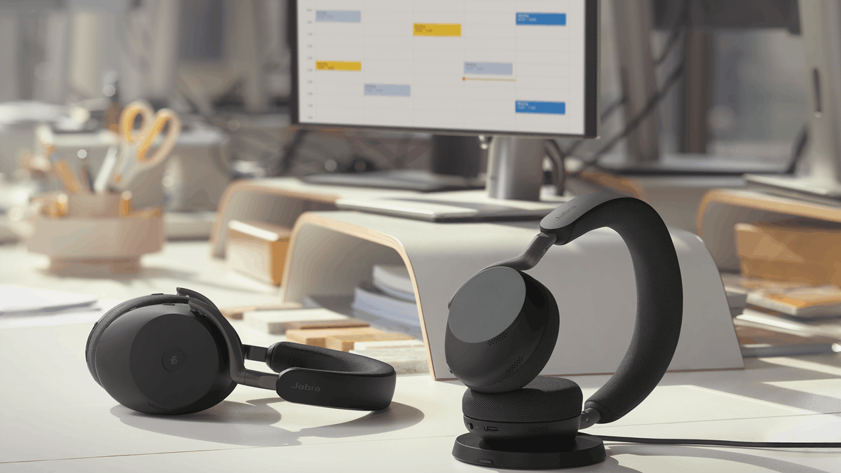 Jabra Evolve3 85 lying and Evolve3 75 Charging on an office desk beside a computer monitor