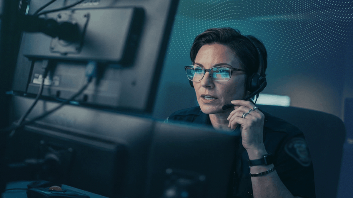 A woman wearing a headset monitoring emergency response systems at a control center