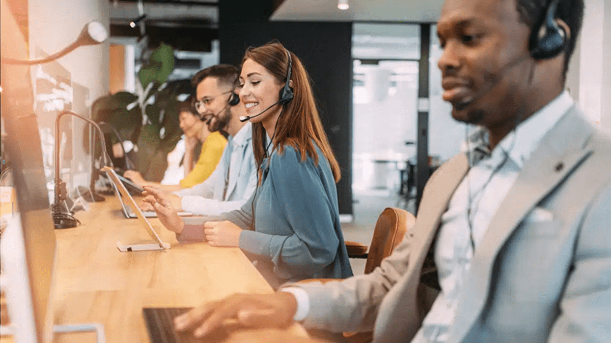 Call center employees wearing headsets and working at computers in a modern office