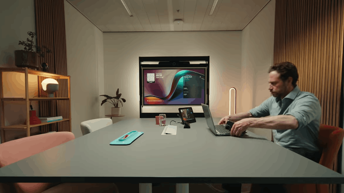 A person in a meeting room setup with ClickShare Hub and laptop-based conferencing