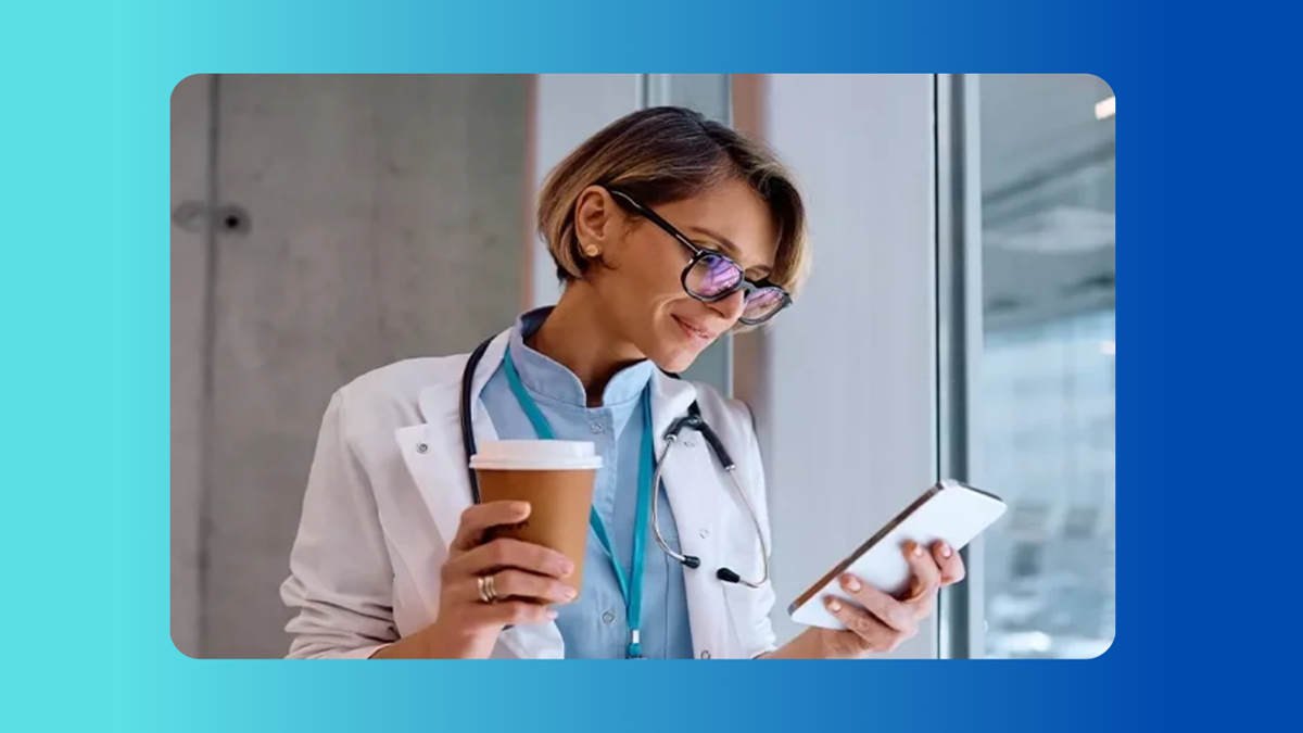 A smiling doctor holding a coffee cup and checking EHR-integrated contact center updates on a smartphone