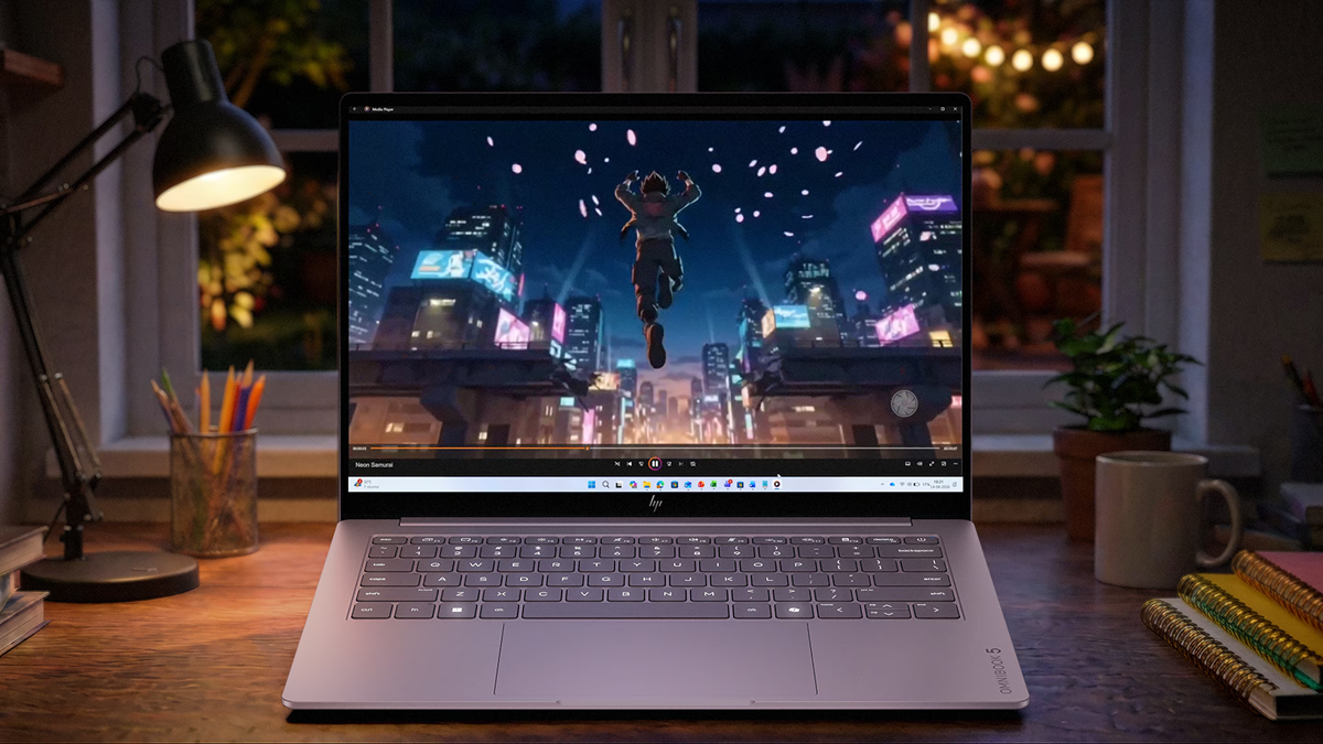 HP OmniBook 5 laptop playing video on a desk in a warmly lit room