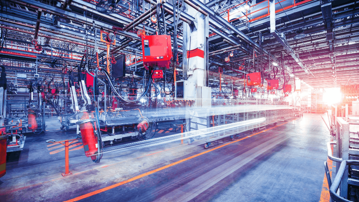 Industrial manufacturing facility with automated robotic equipment, overhead machinery, and production lines inside a large factory