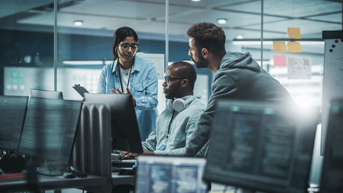 Team of professionals collaborating around computer screens in a control room or operations center