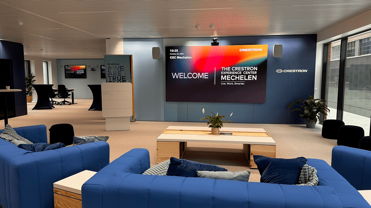Reception and presentation area at the Crestron Experience Center Mechelen with a large welcome screen and blue seating arrangements