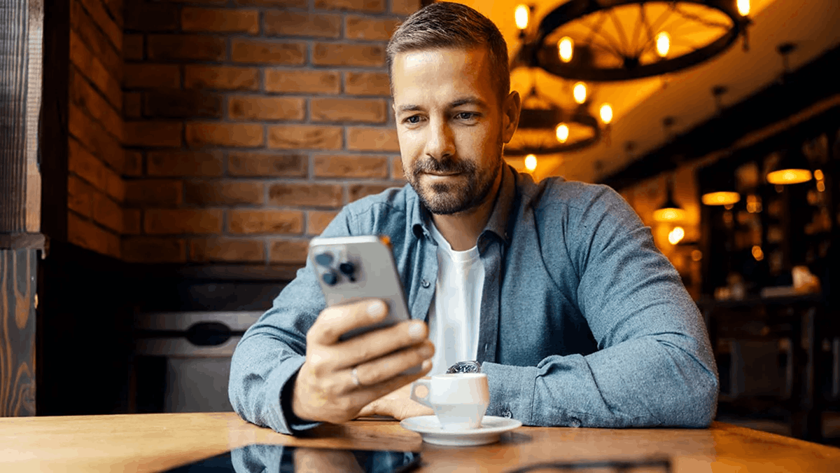 A man using a smartphone while sitting at a café table