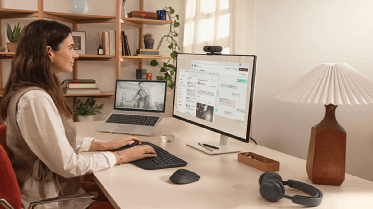 Home office setup featuring a professional using a Logitech keyboard and mouse with dual-screen productivity workspace