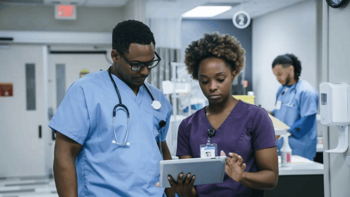 Hospital clinicians reviewing patient information on a tablet, illustrating connected healthcare systems that support real-time data access and care coordination