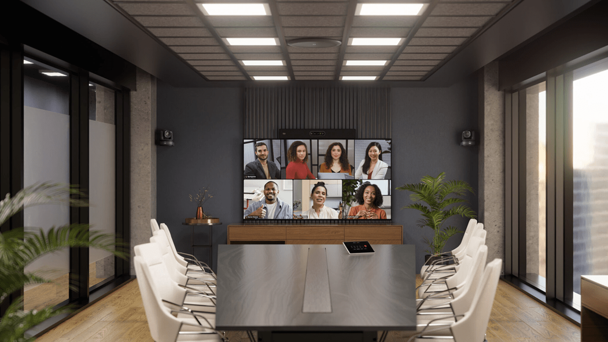 A hybrid meeting room featuring Cisco Room Vision PTZ hardware with remote meeting participants displayed on the screen