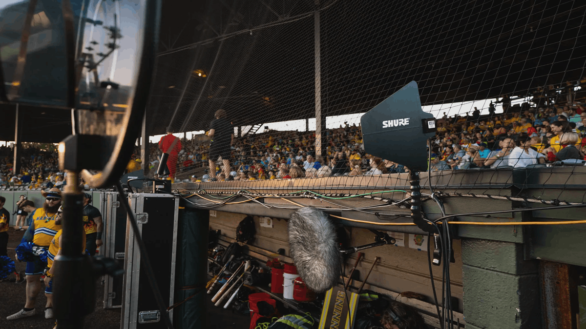 Shure broadcast microphone capturing live sports audio at a crowded stadium